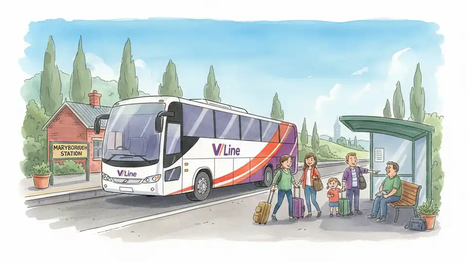 V/Line coach bus at regional station stop with passengers waiting, countryside visible in background